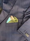 Pocket square with drawing of three mountains blue sky and green grass folded in men's blue blazer