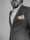 Pocket square with drawing of three mountains blue sky and green grass folded in men's blue blazer